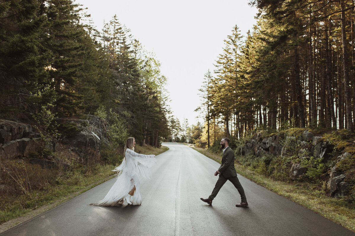 A couple walks towards each other in the road of Acadia