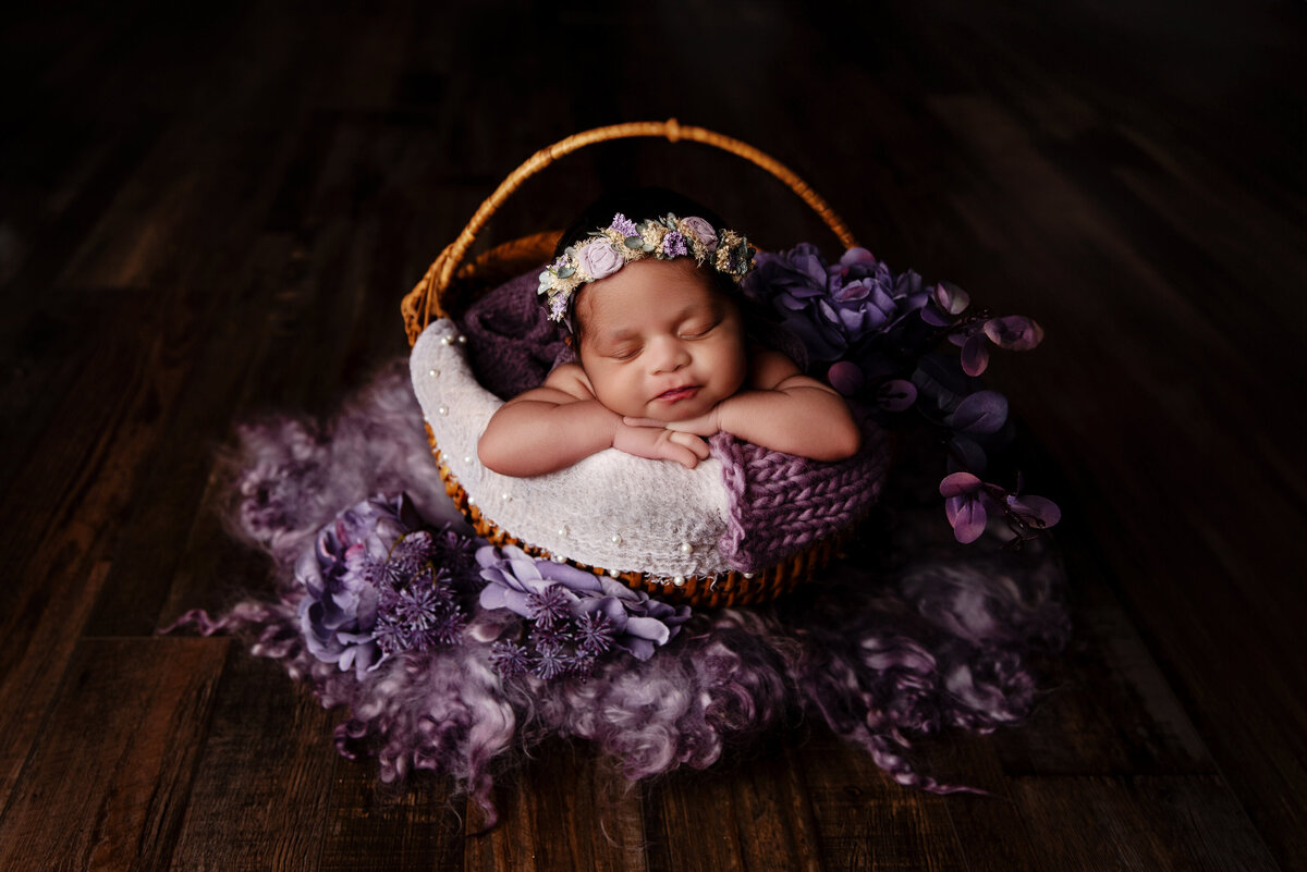 Mom with baby boy in a milk bath holding baby surrounded by pink and purple flowers