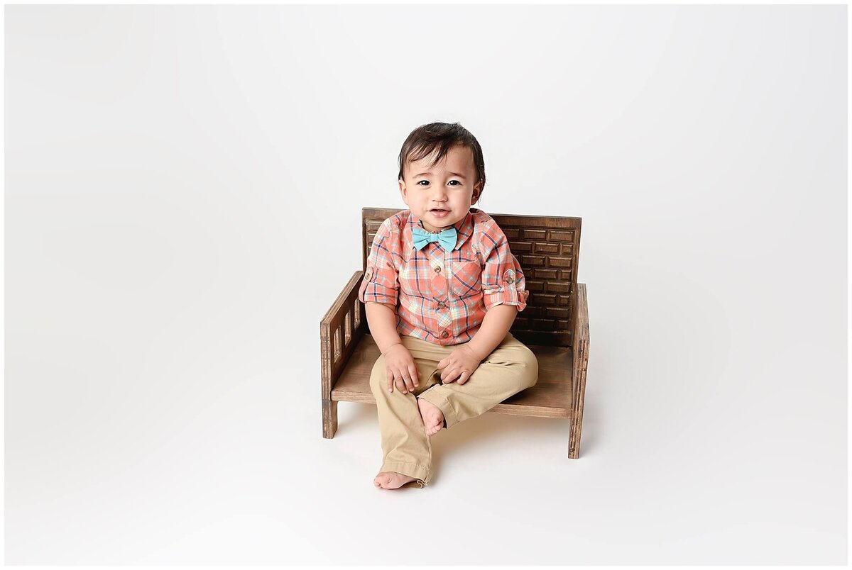 Little toddler boy sitting on small bench .