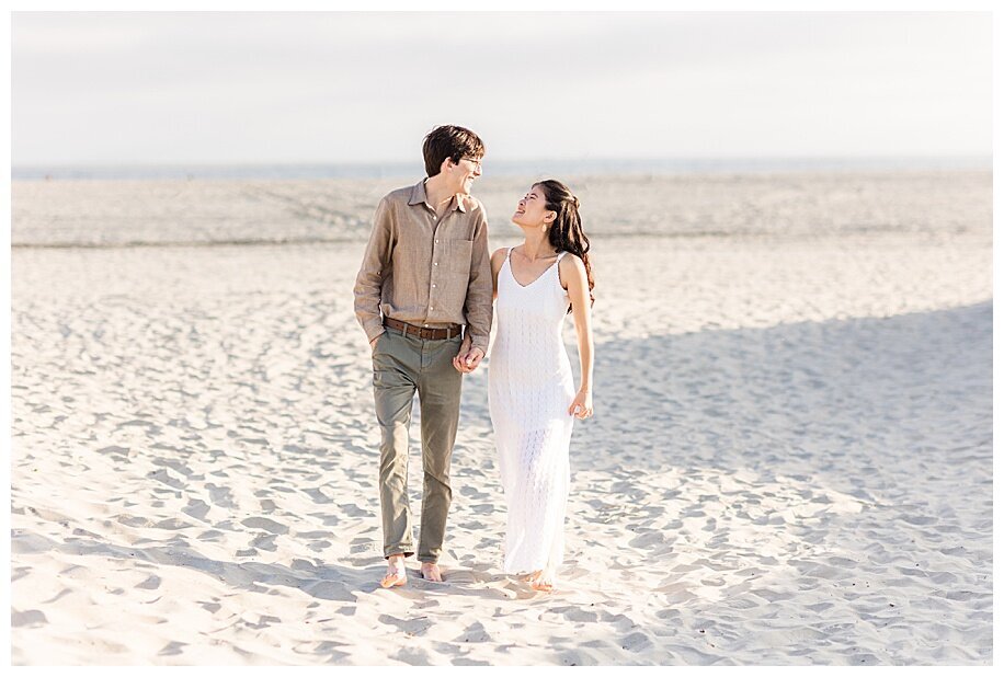 egaged couple walking in sand in san diego