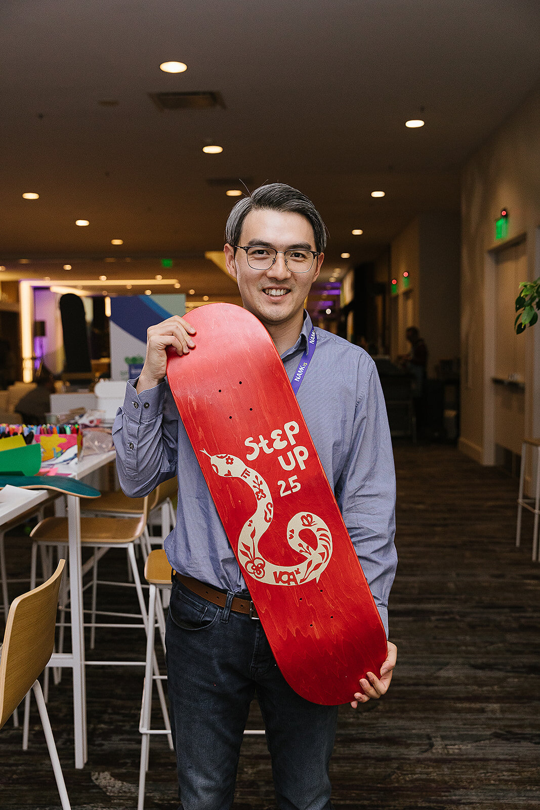 man holding a skateboard with a snake that he designed on it 