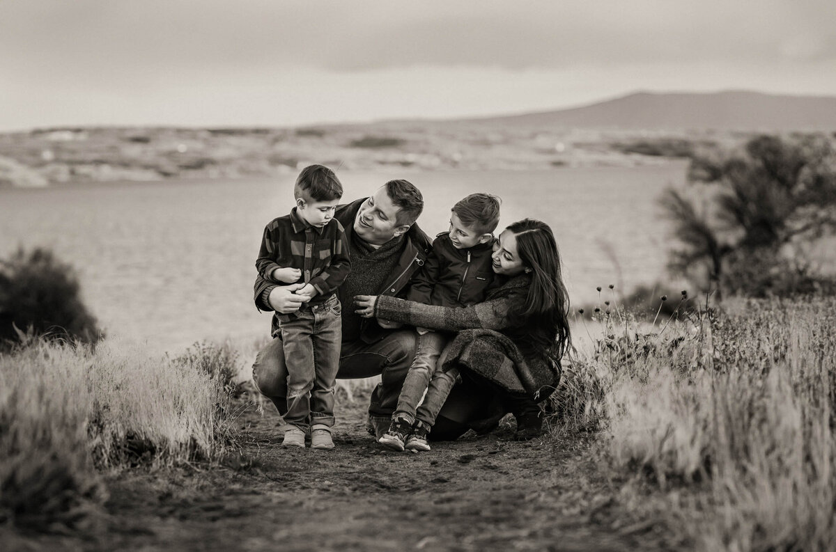 Family snuggling close while squatting down together during a photo session, sharing a quiet, loving moment.
