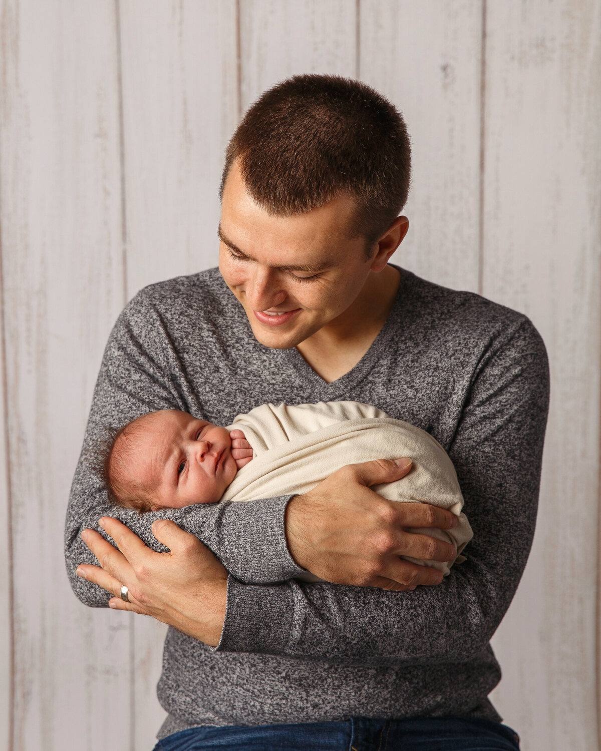 Portrait of a newborn baby cradled in Dad's arms