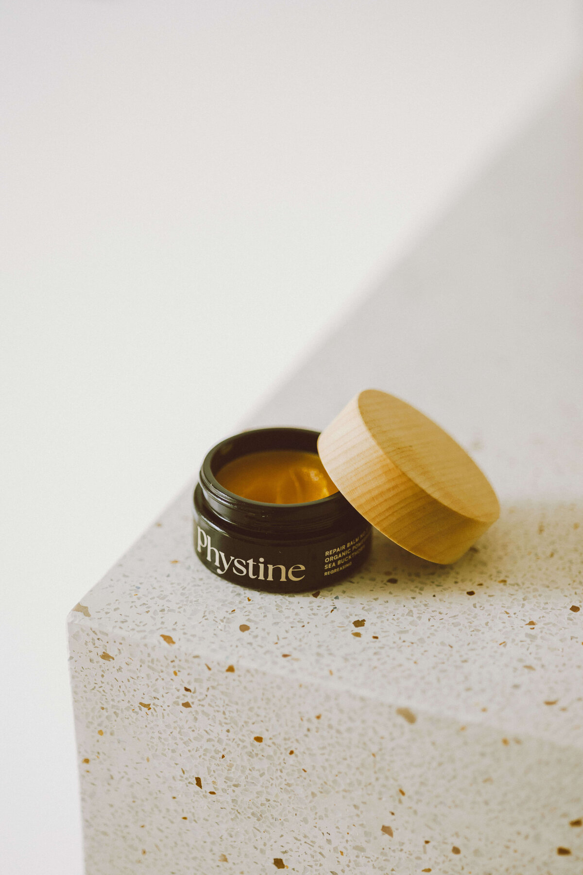 Skin care brand photography of open skincare balm jar on stone surface