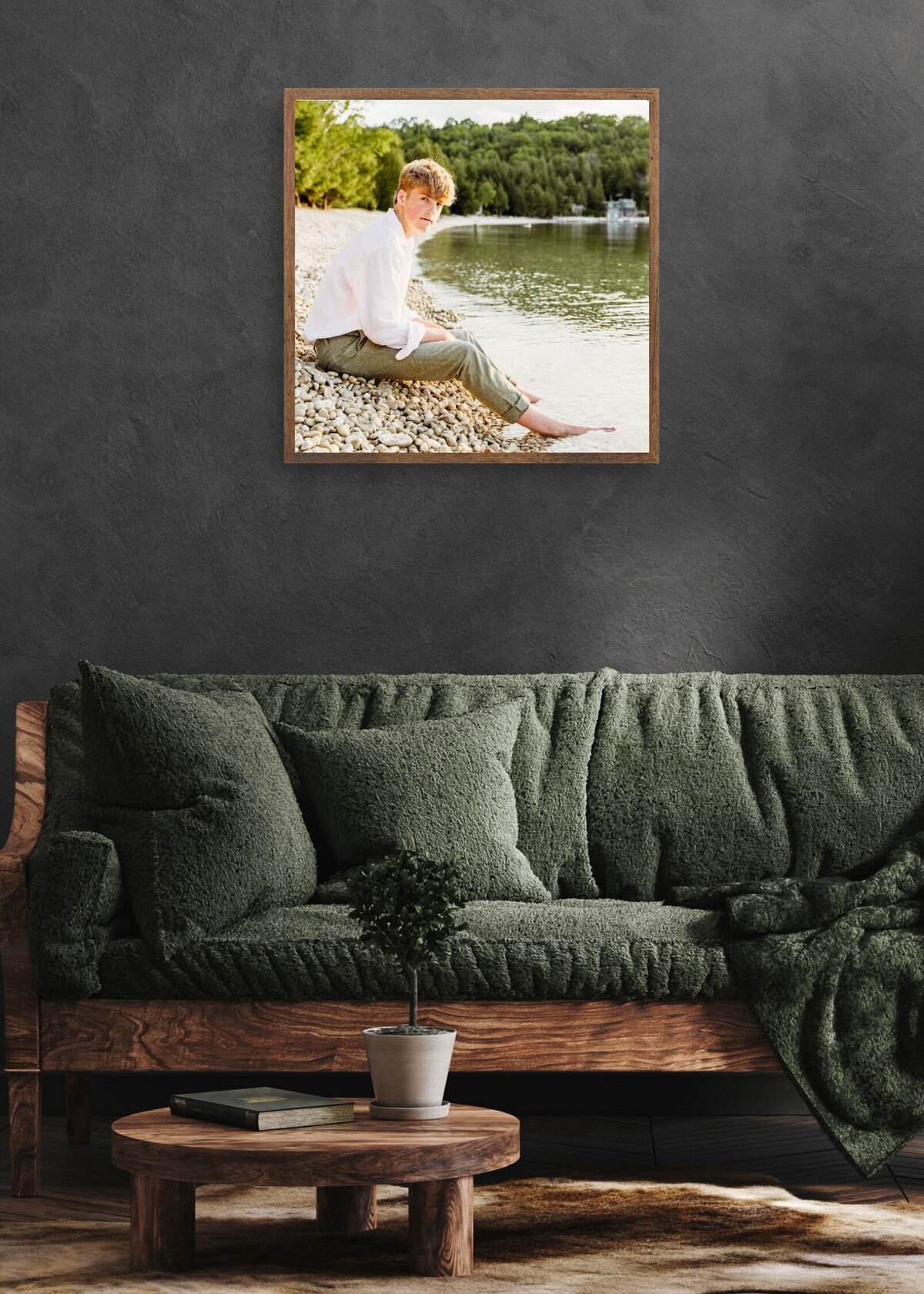 dark and moody living room with a green coach and grey walls featuring a senior photo of a boy taken in  Door County