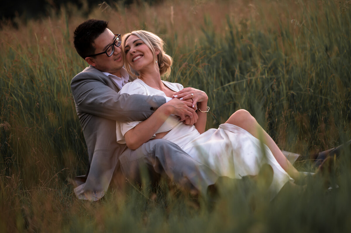 couple sitting in a field celebrating their engagement