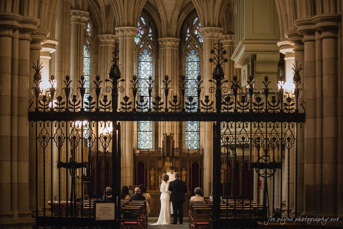 A couple saying their vows in a small wedding in a chapel.