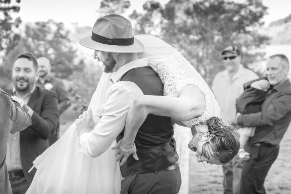Groom with laughing bride over shoulder