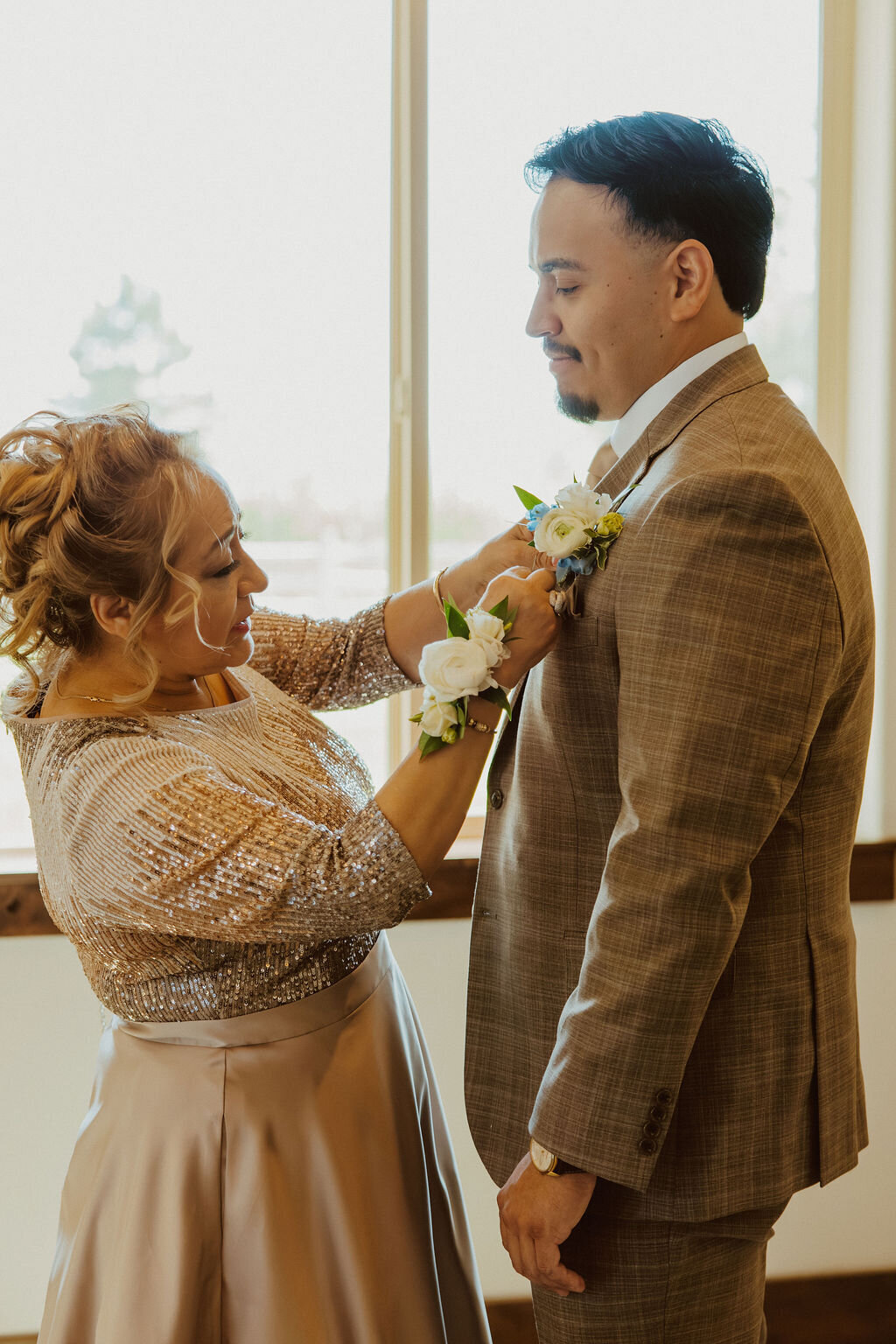 Groom's boutonniere being pinned before the ceremony