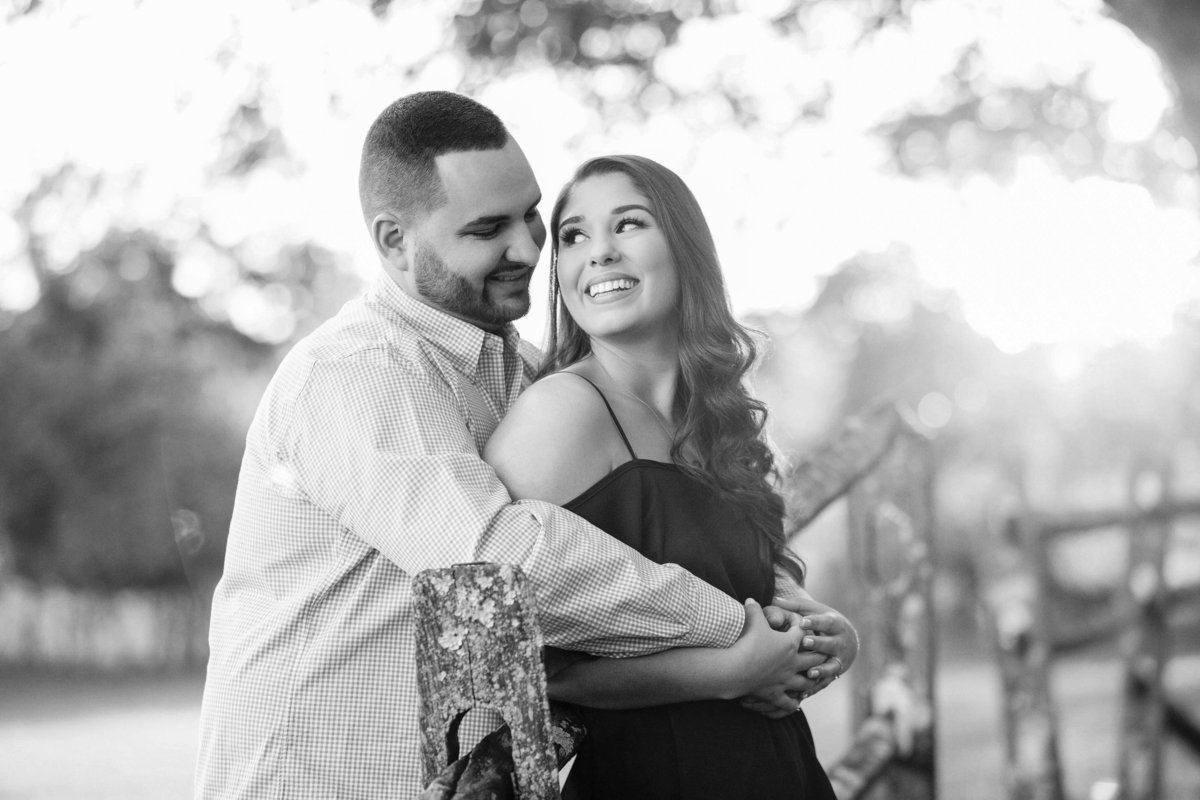 engaged couple cuddle by fence at bayonet farm