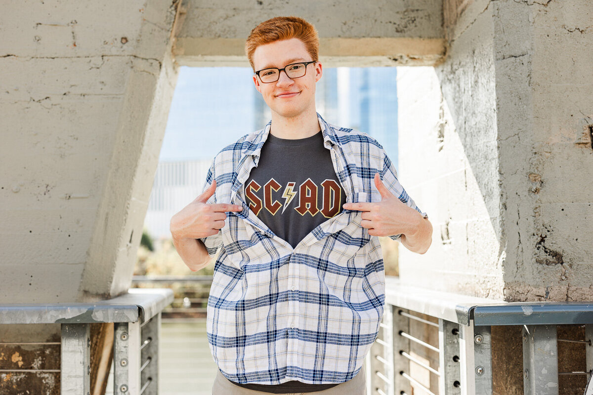 Boy unbuttoning his shirt to reveal an SC AD tshirt