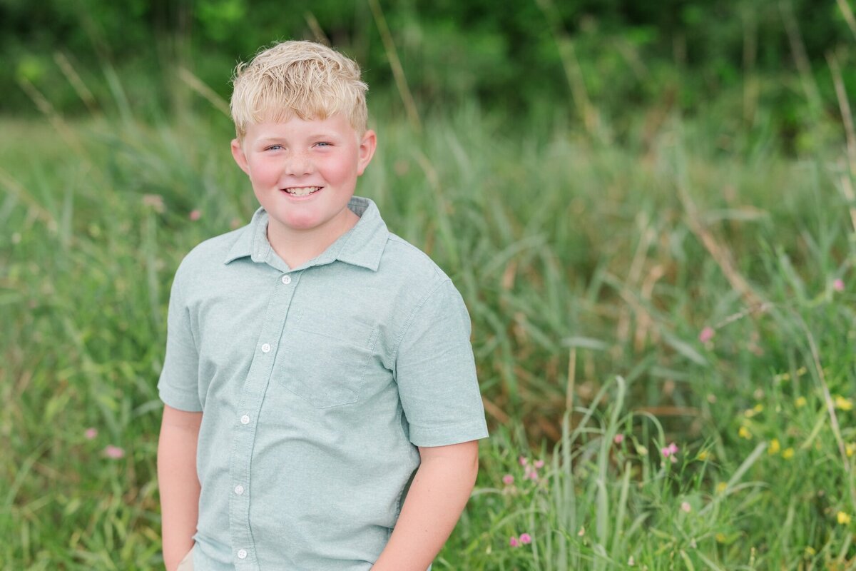 a young boy smiling in a light green button up shirt