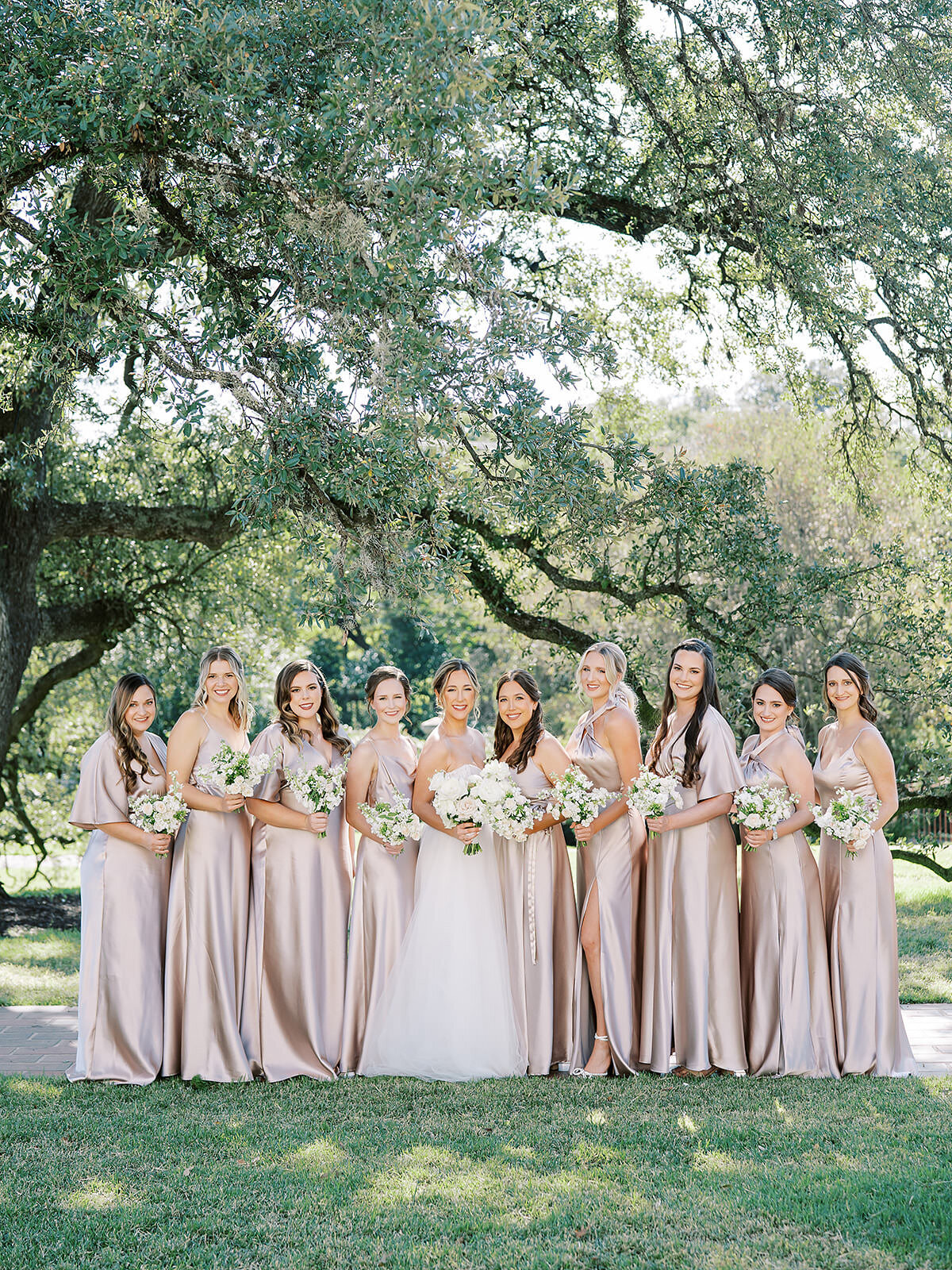 a group of bridesmaids in blush satin dresses pose together at the commodore perry estate