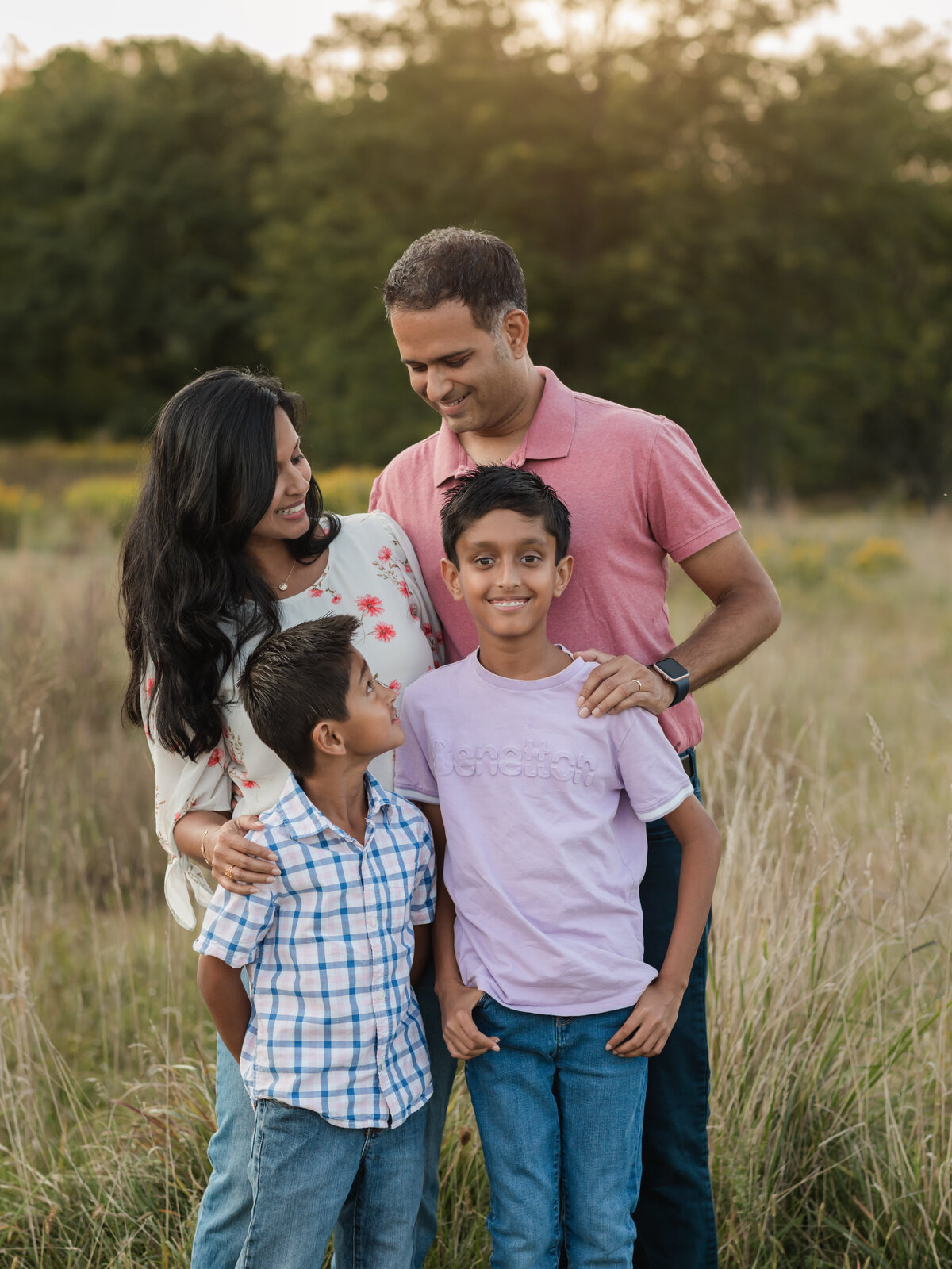 mom dad and two sons posing in field for family photos cleveland family photography