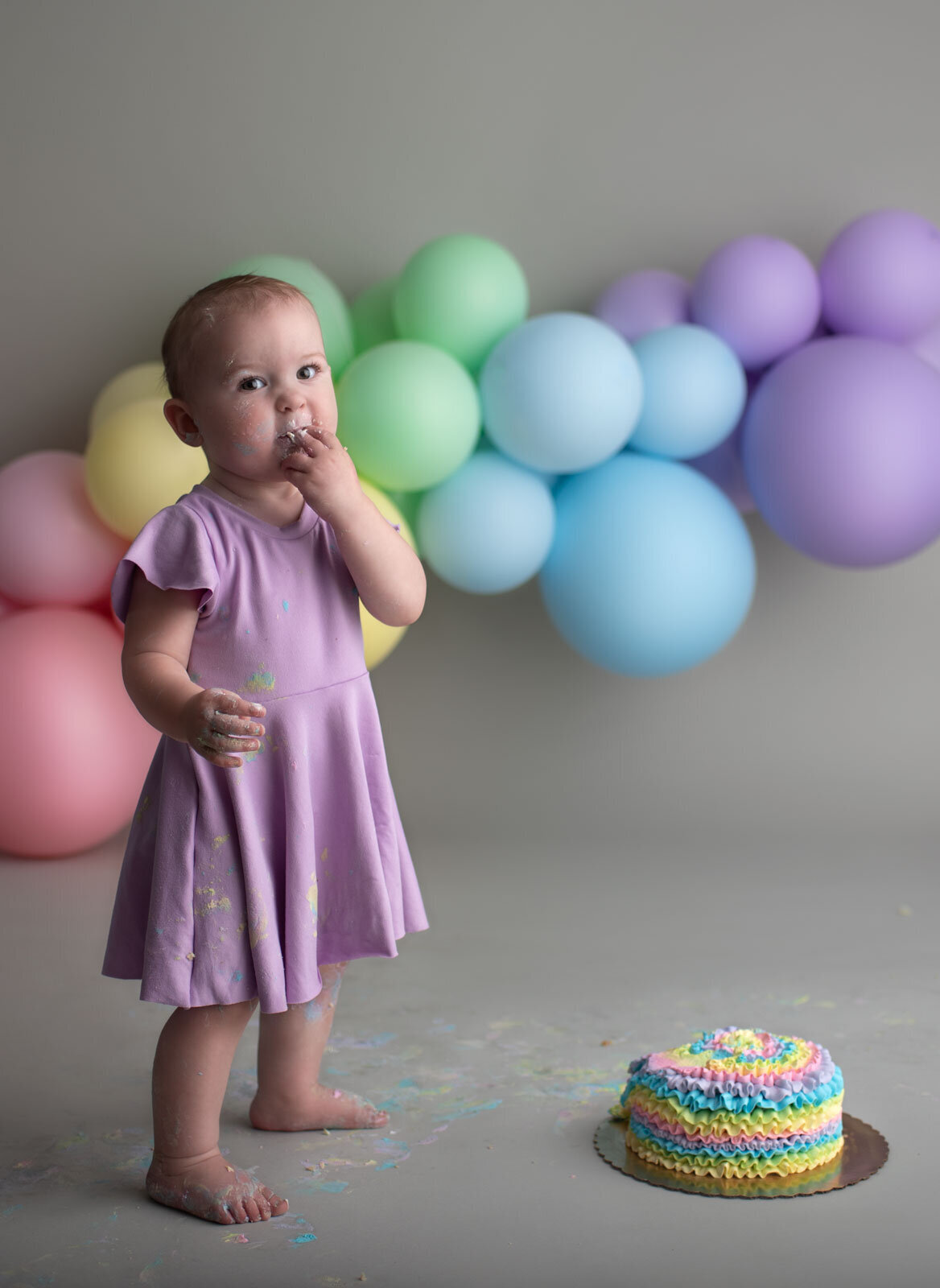 baby standing and eating cake at her saint louis cake smash photo session