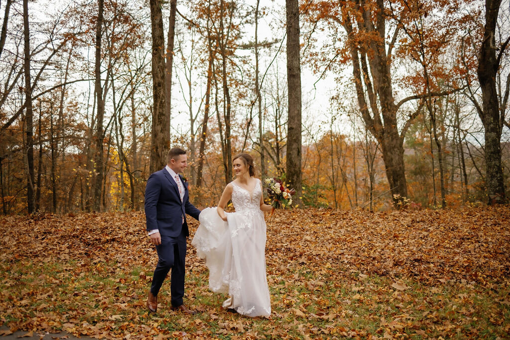 fall Gatlinburg elopement with groom carrying his brides train through the woods together