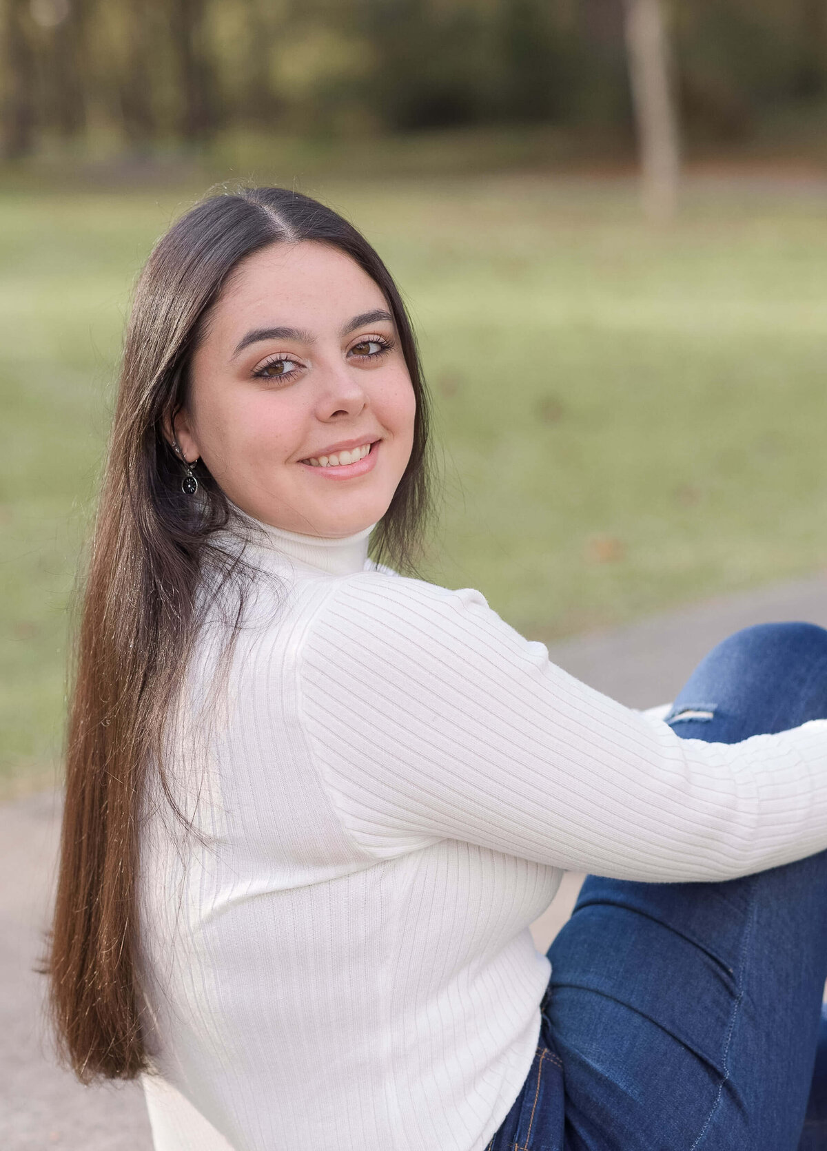 girl with long dark hair looking at the camera and smiling softly during her senior session with Elizabeth Klusmann Photography