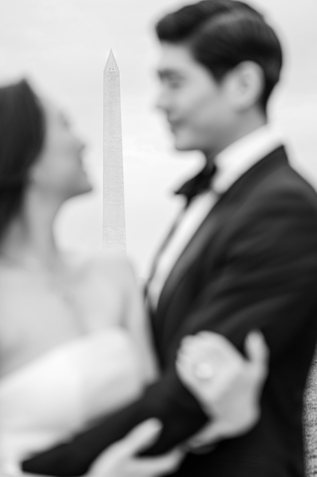 A loving engaged couple embracing next to the Washington Monument in a black and white photo while enjoying their Raleigh wedding photos by JoLynn Photography
