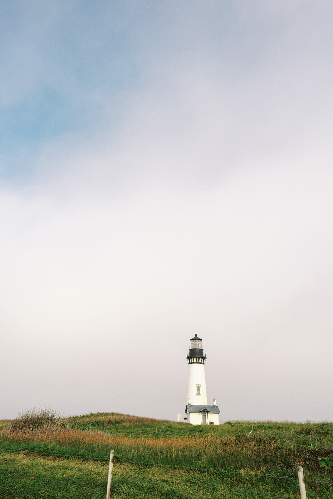 Yaquina Head Lighthouse with blue skies and clouds. 