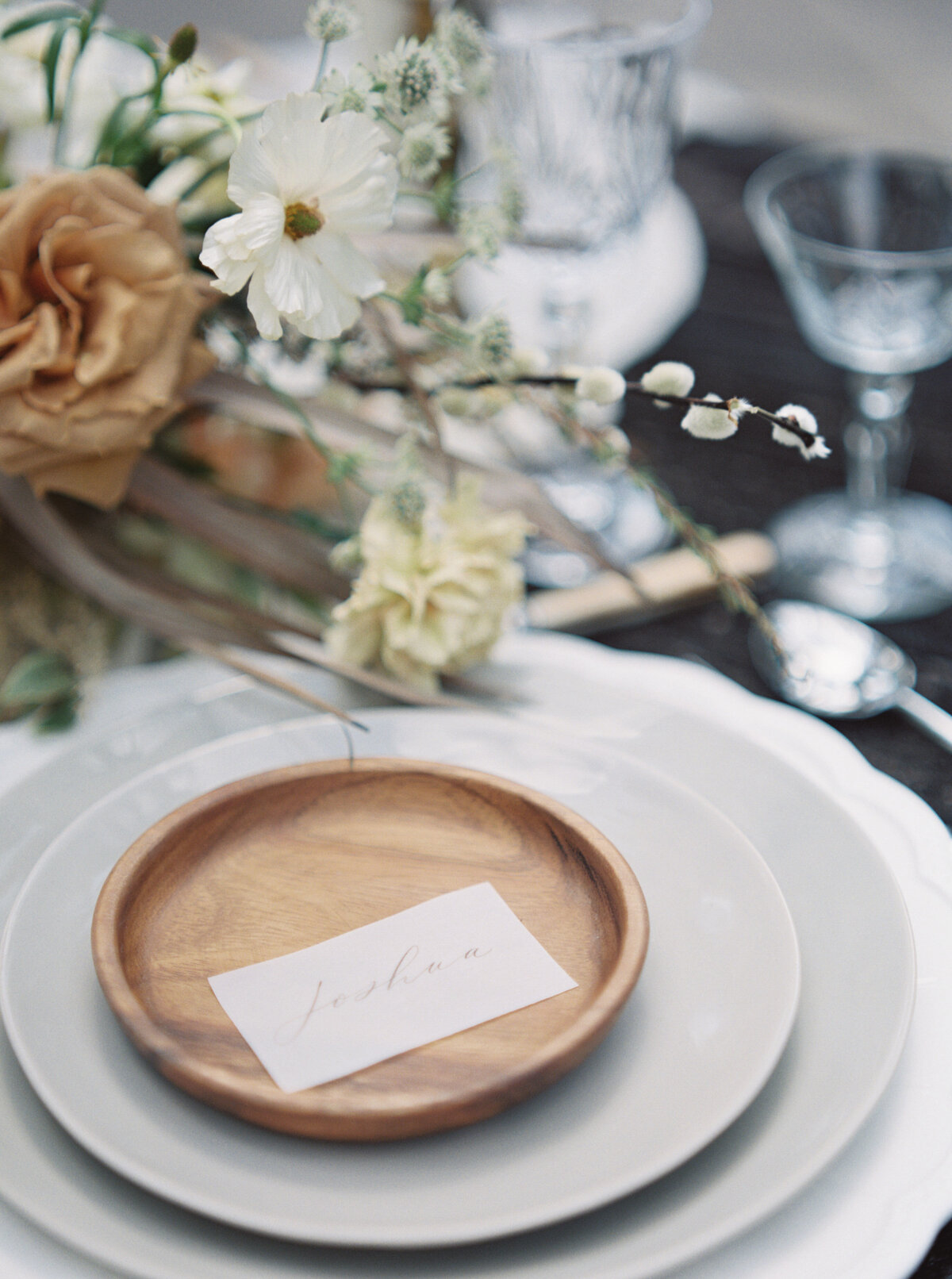 A seating place card sits atop a wooden bowl plate.