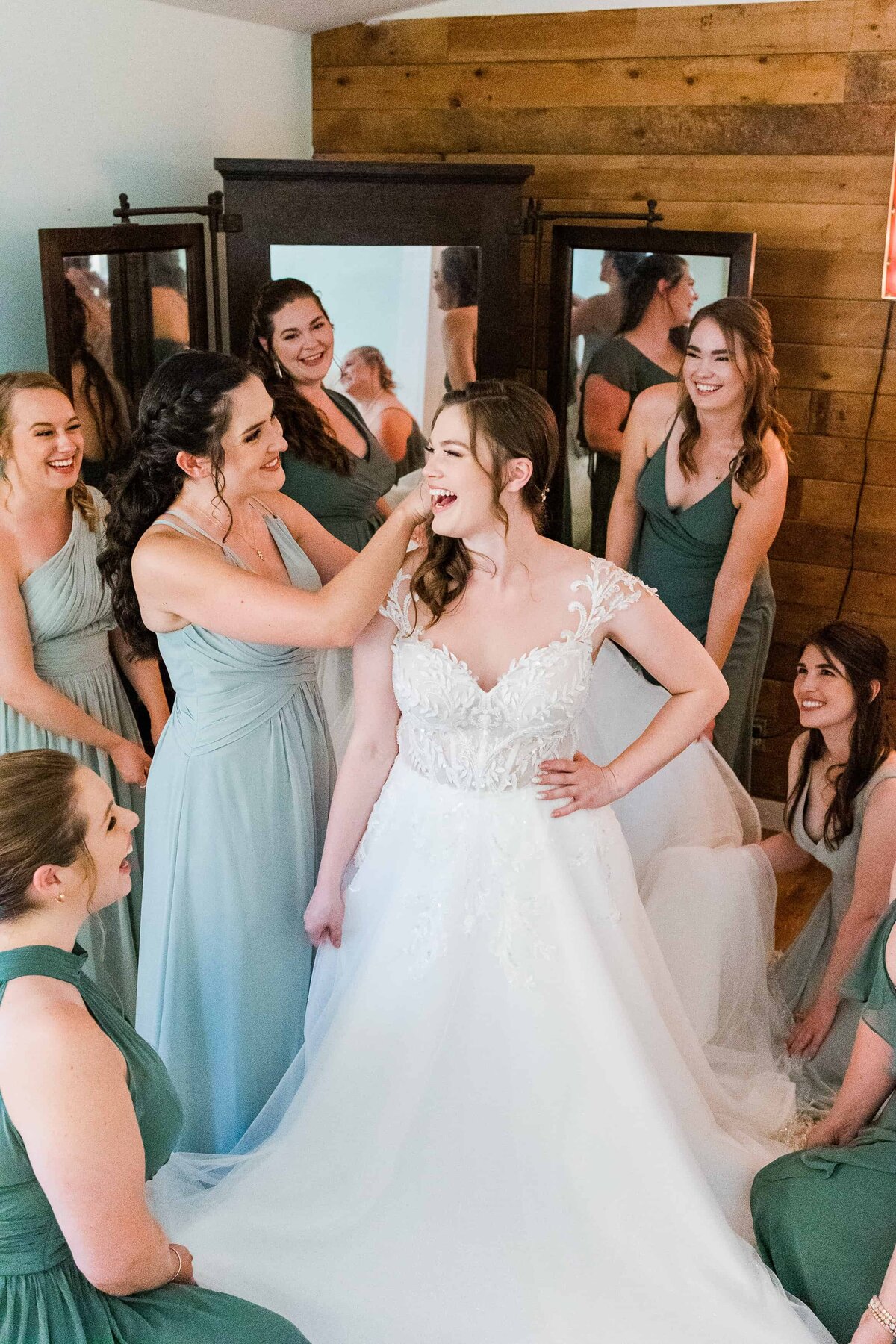 Bride in white dress, getting ready with six bridesmaids in sage green dresses at Rein Fire Ranch near Seattle Washington