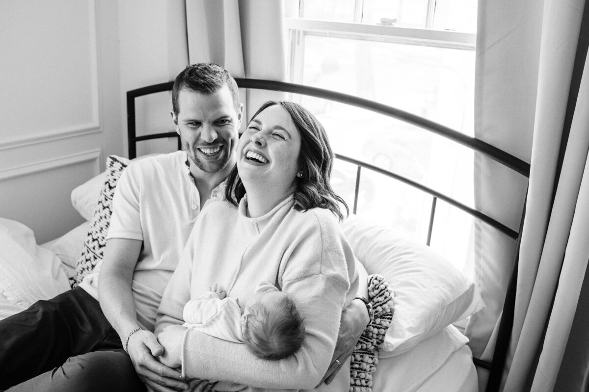 Couple laughing while holding baby during family photography session.