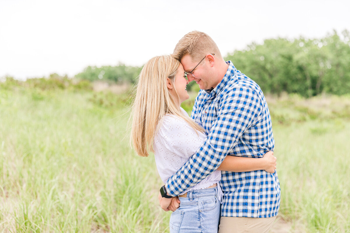 Light and airy beach engagement forehead to forehead in the beach grass at Mentor Headlands Beach