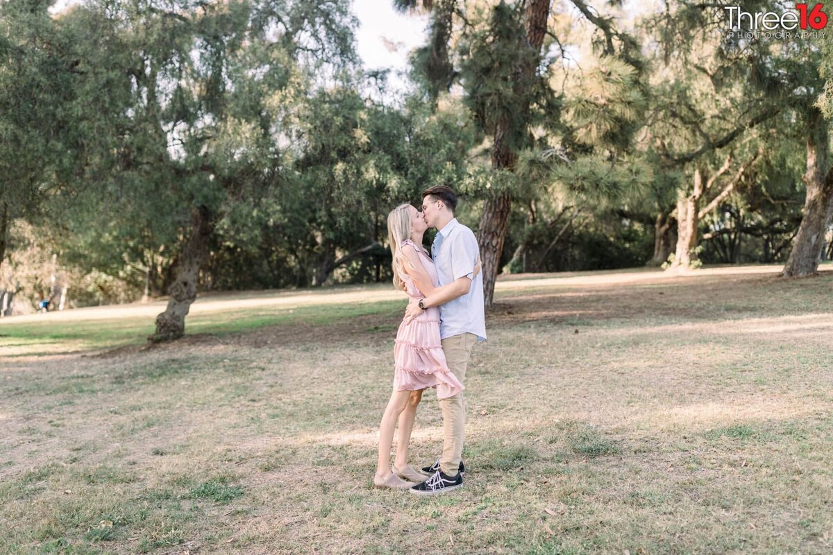 Engaged couple share a kiss on the grounds of the Huntington Beach Library