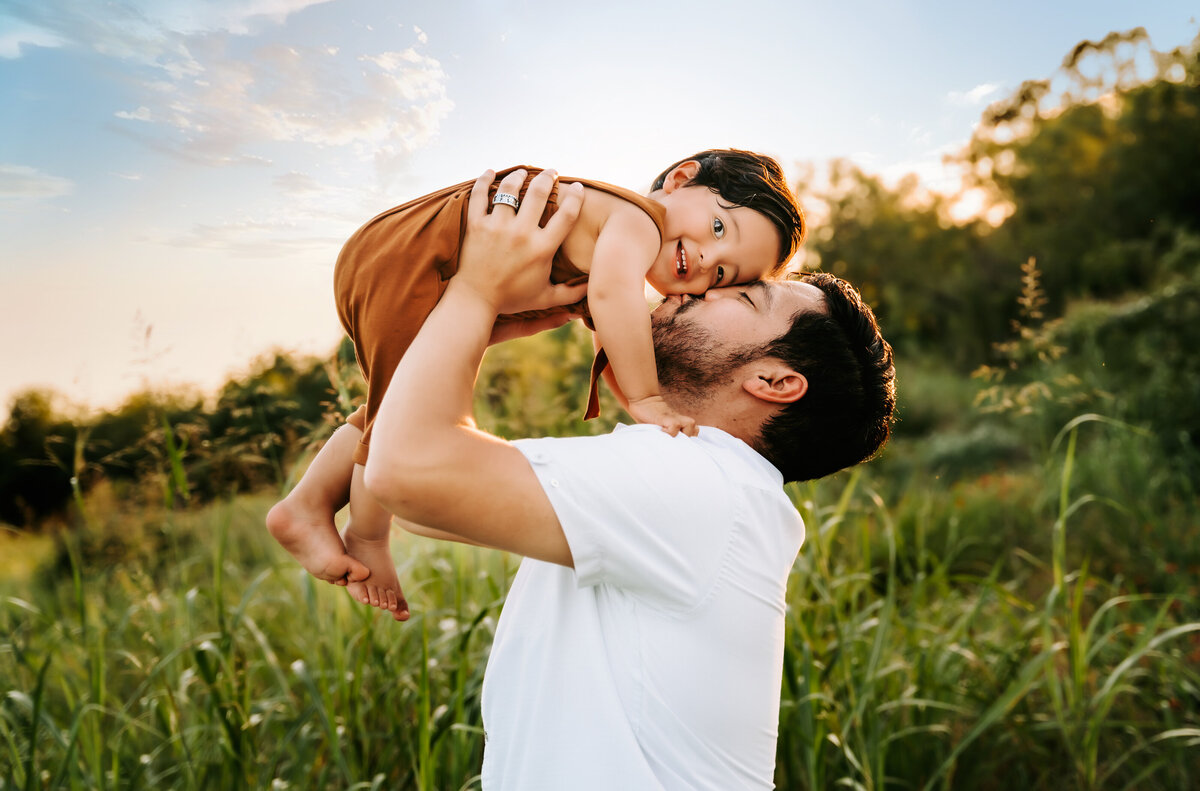 Family Photographer, a father lifts his baby son and gives him a kiss