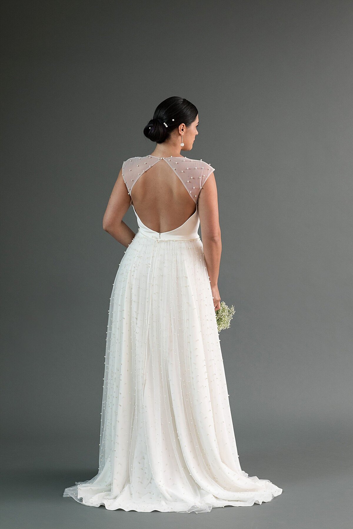 The gathered pearl net skirt of this wedding dress style has a short train.