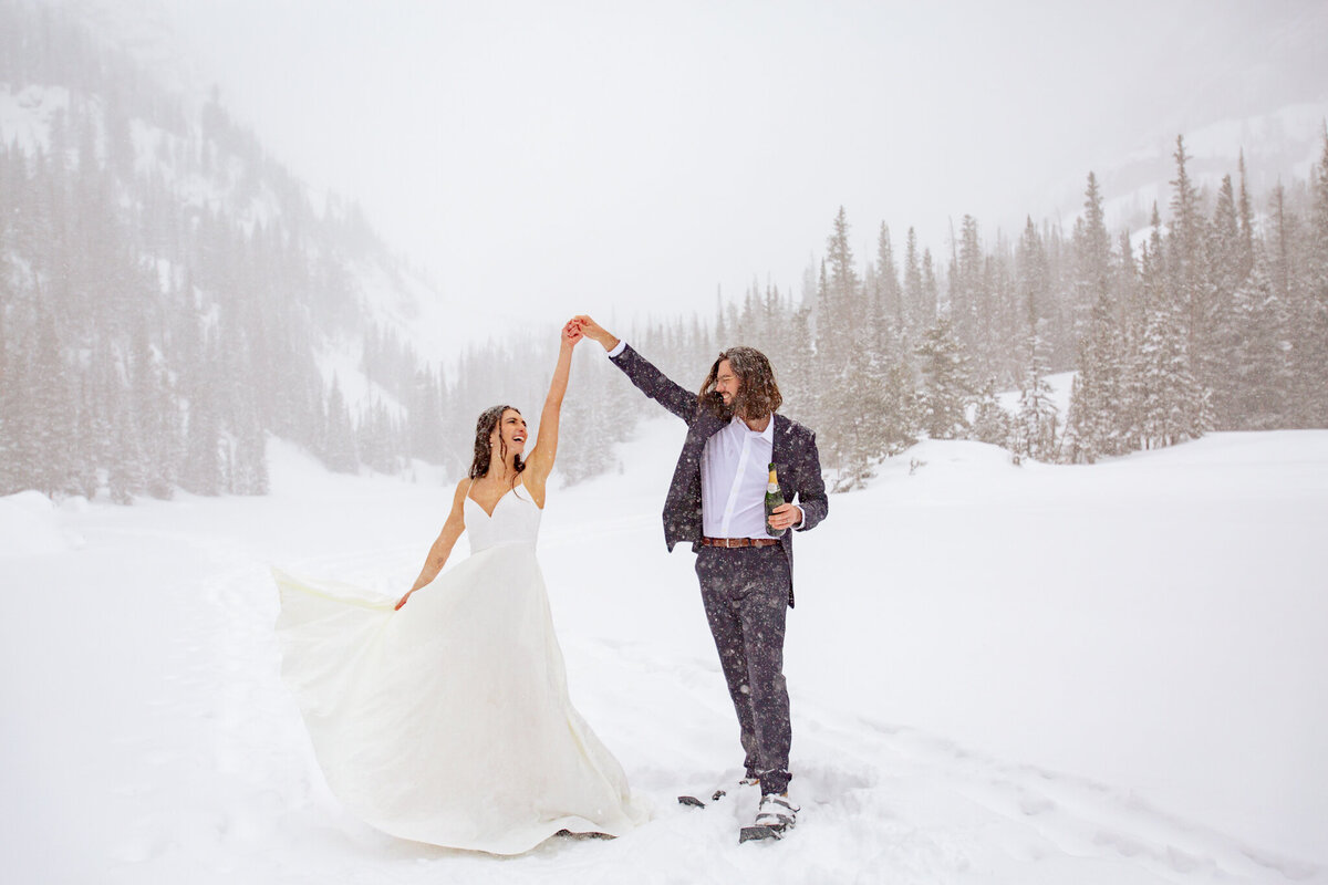 Groom spins bride on a frozen lake during a winter storm in Rocky Mountain National Park