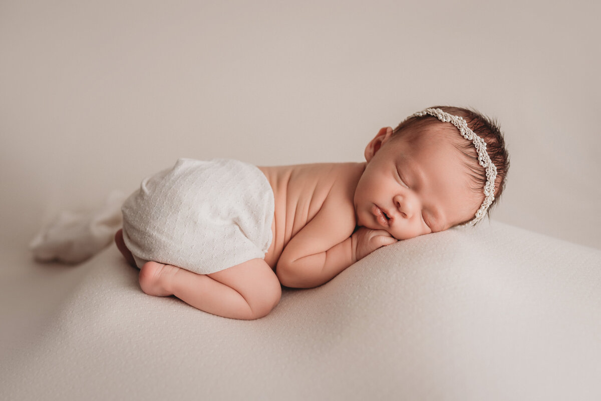 baby girl at her newborn portrait session at Marietta, GA newborn photography studio sleeping on tummy and curled up while posing for her newborn portrait