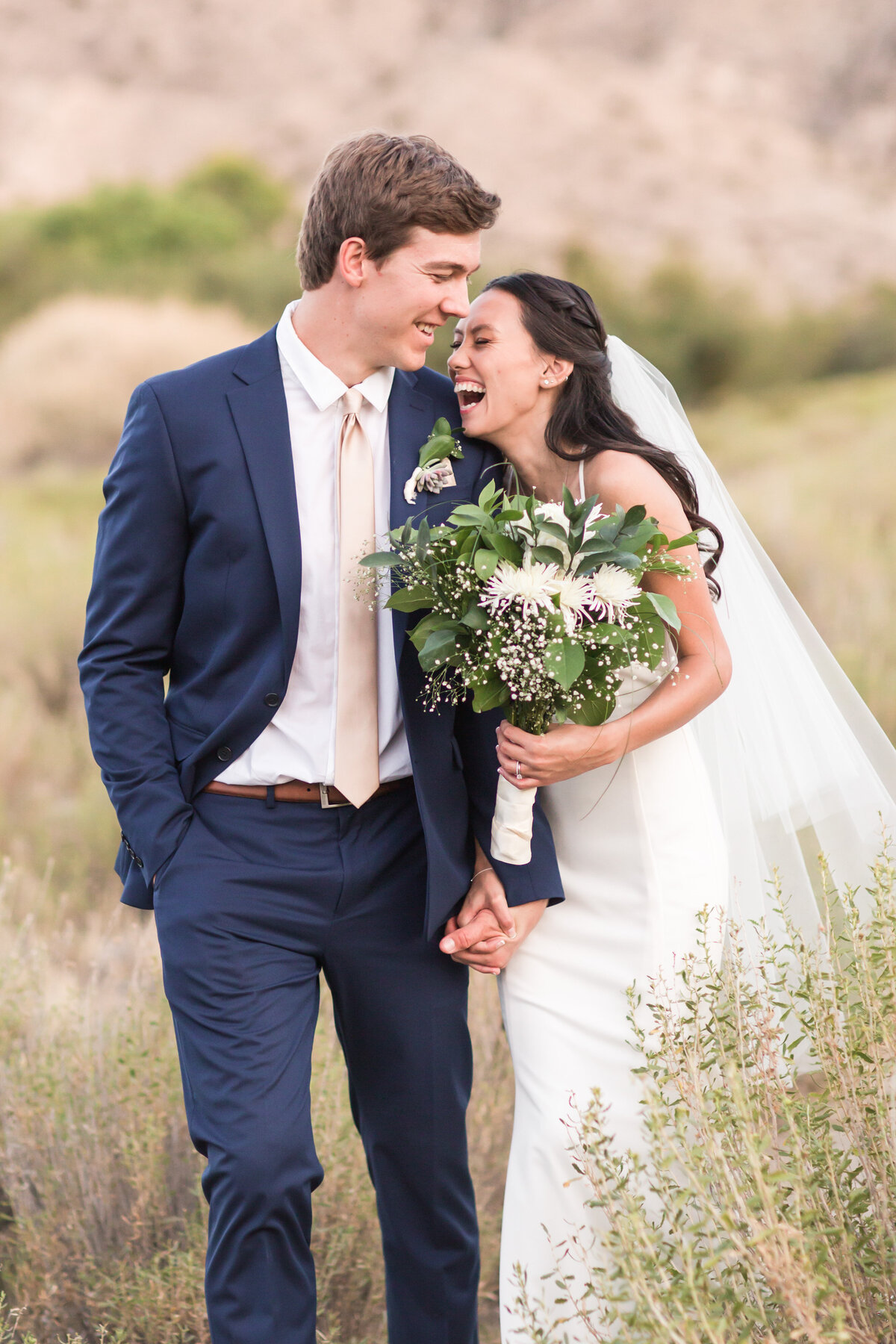 bride and groom walking in a field laughing