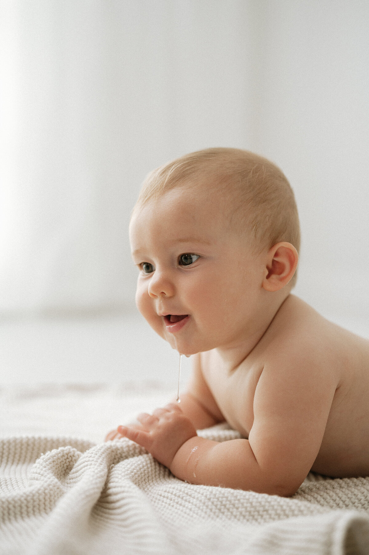Baby photography of a young baby lying on a white blanket