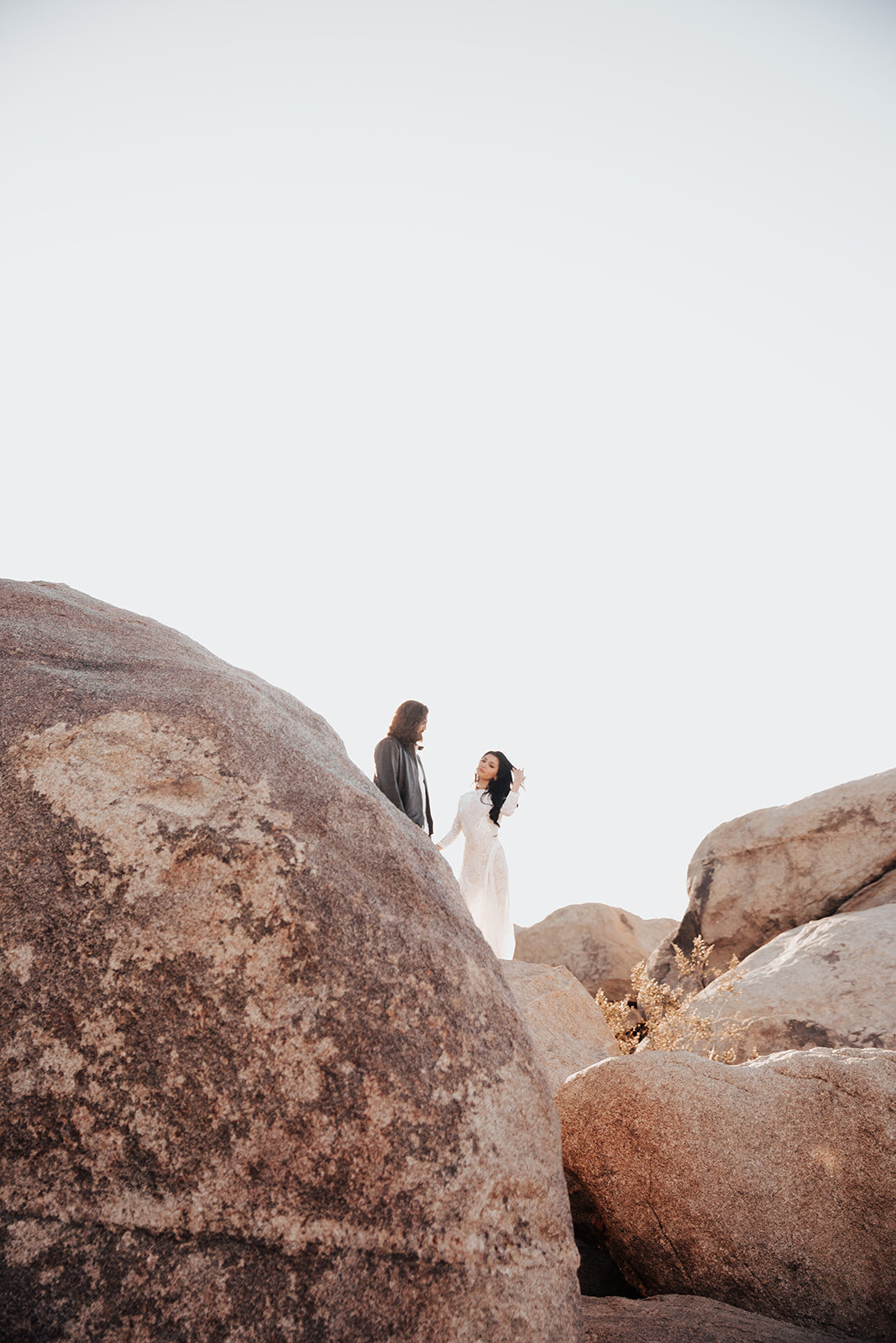 Wedding couple walking through rock formation in Joshua Tree National Park