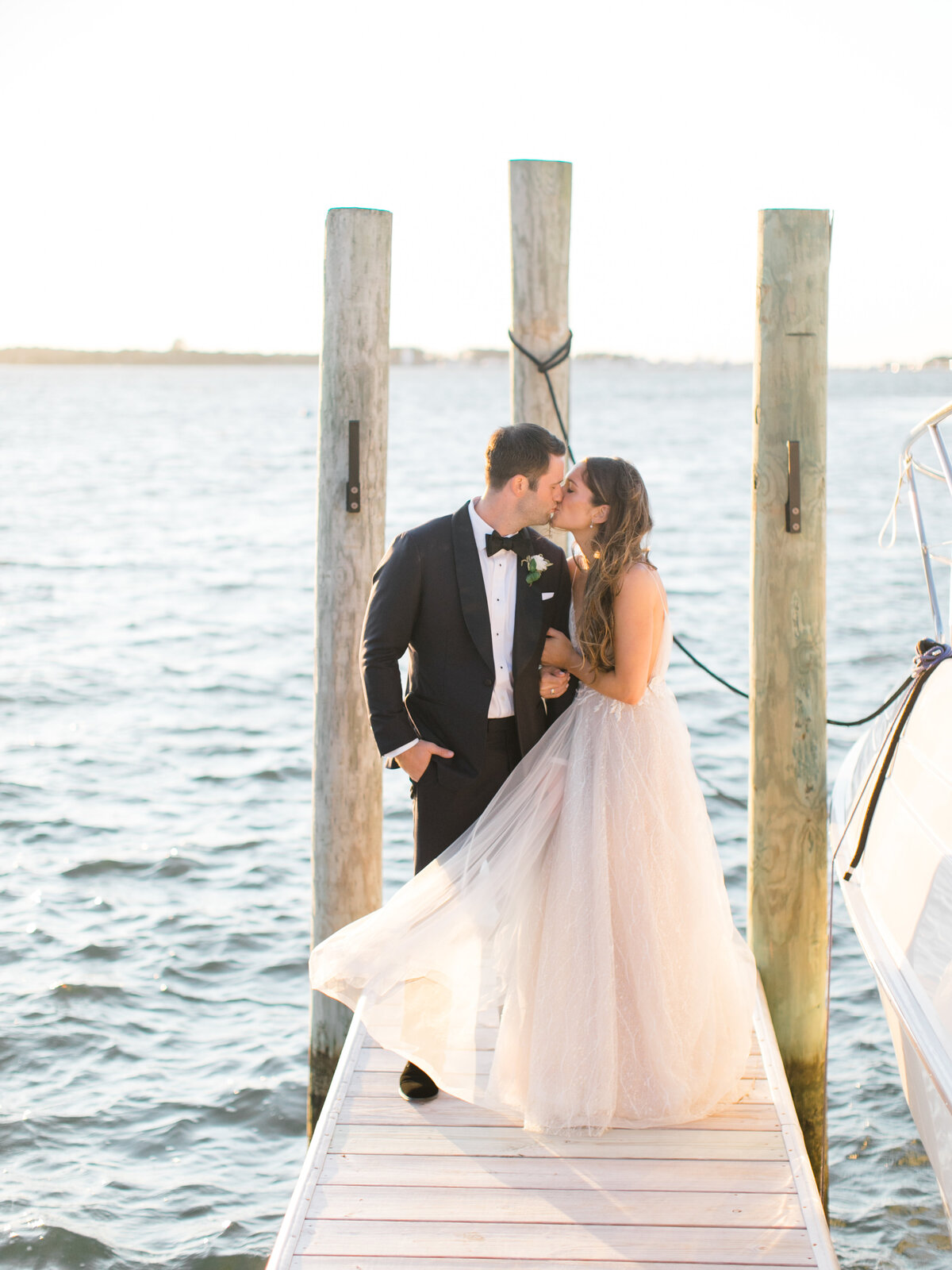 bride and groom staking an a dock on a lake kissing