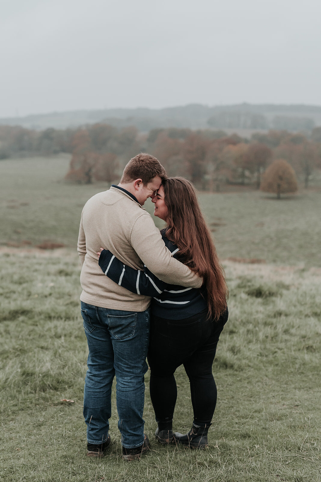 Couple stand facing eachother with arms round each other at Petworth Place 