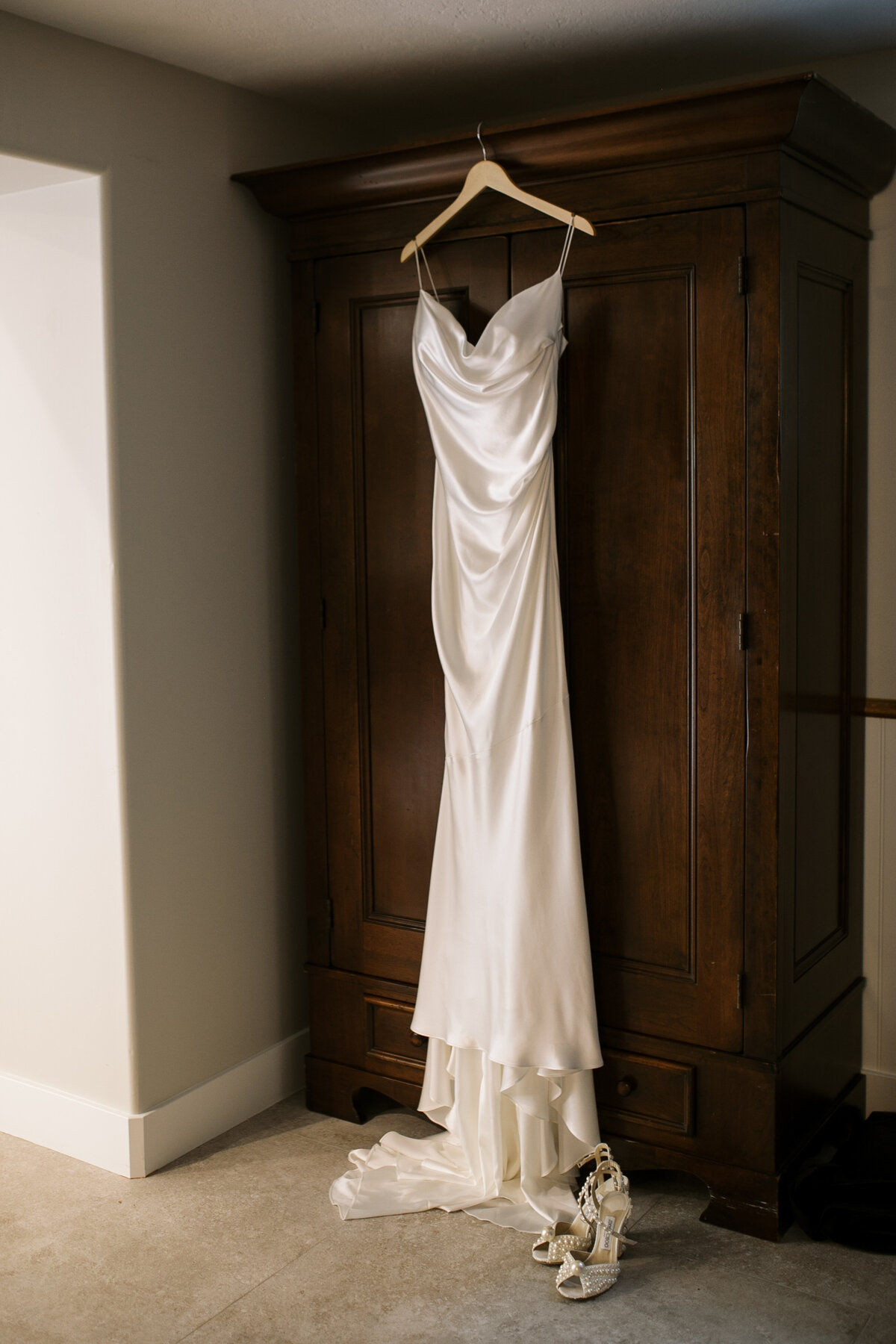 Detail of a satin wedding gown, next to pearl Jimmy Choo heels