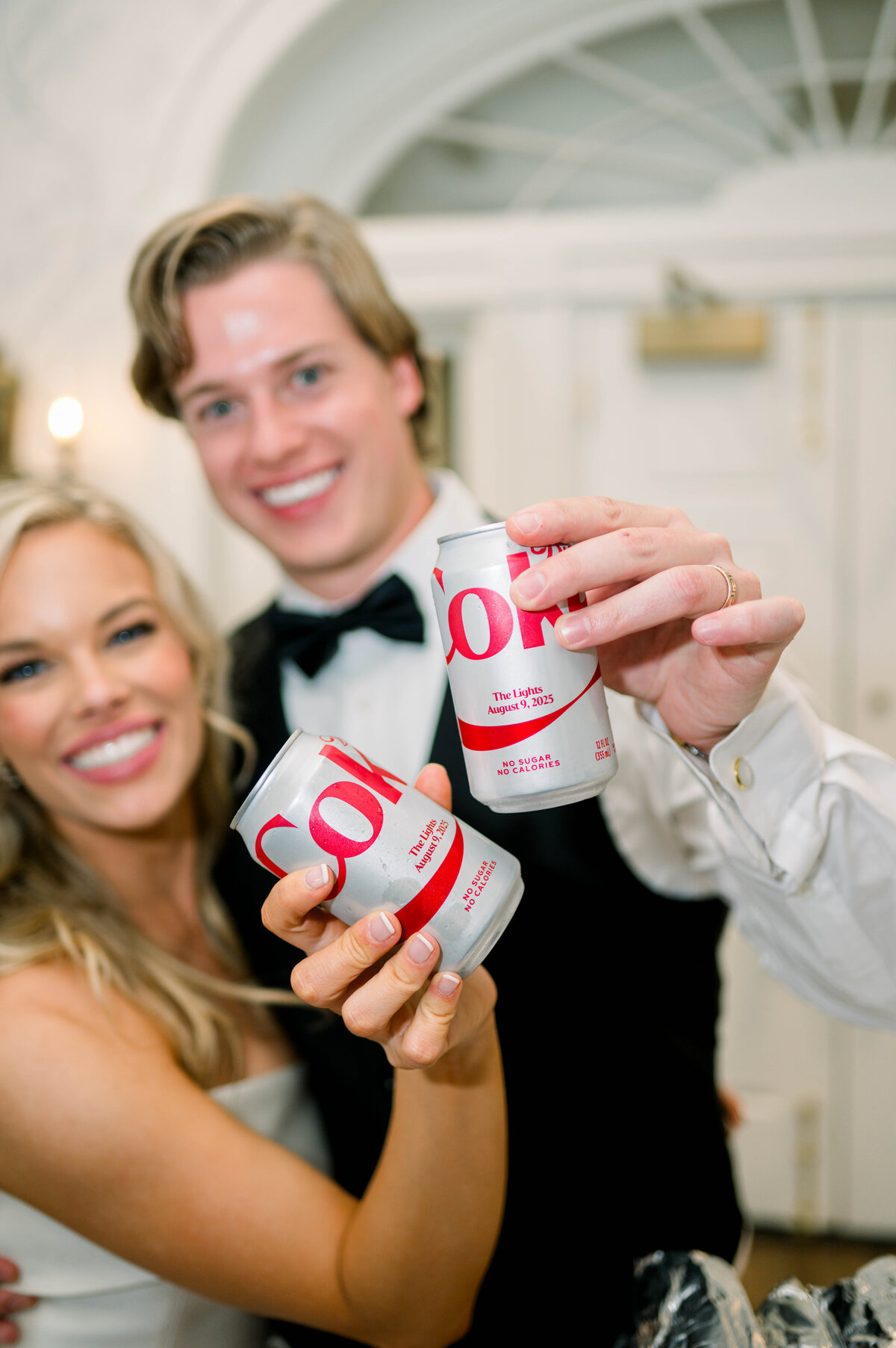 
Couple holding custom Diet Coke Cans made for their wedding reading "The Lights"
