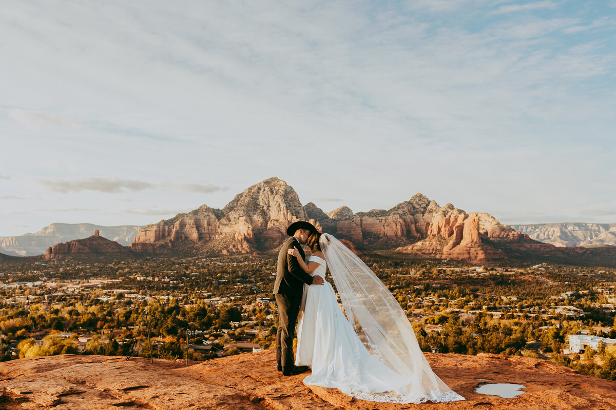 couple kisses with sedona backdrop behind them