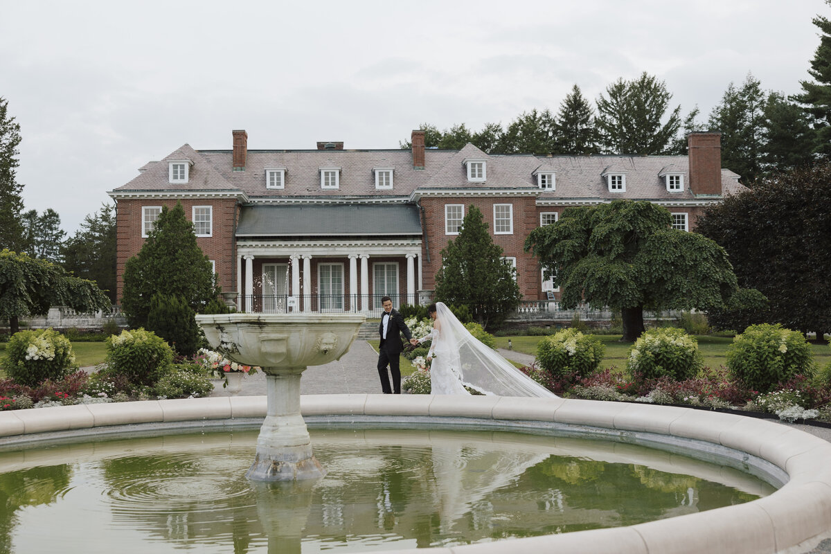 Groom Leads the Bride While Walking Around A Fountain