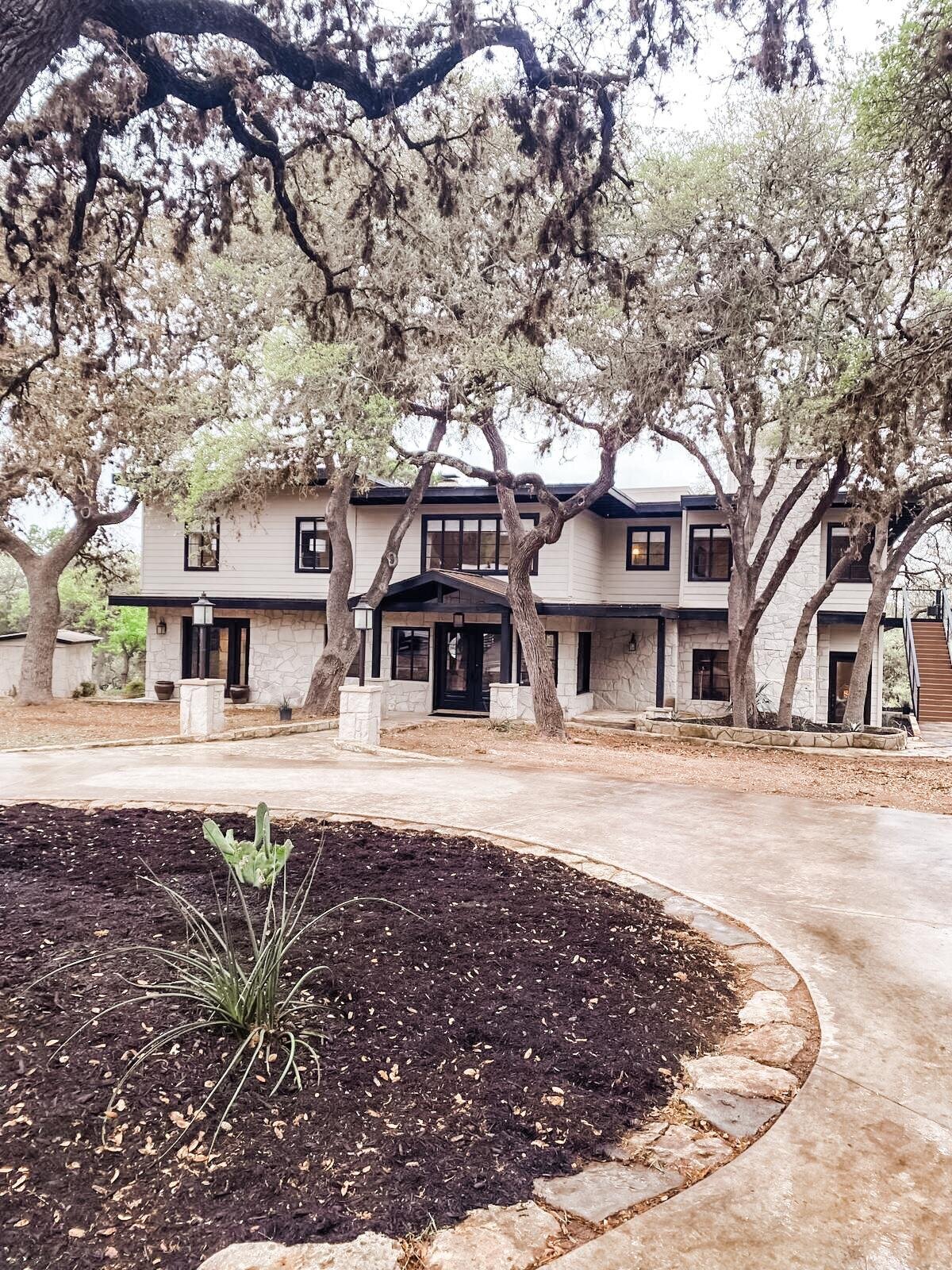 Exterior of large home. Grey walls with black windows and doors.