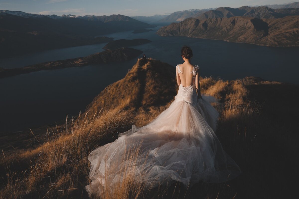 A bride photographed on a mountain overlooking Lake Wanaka.