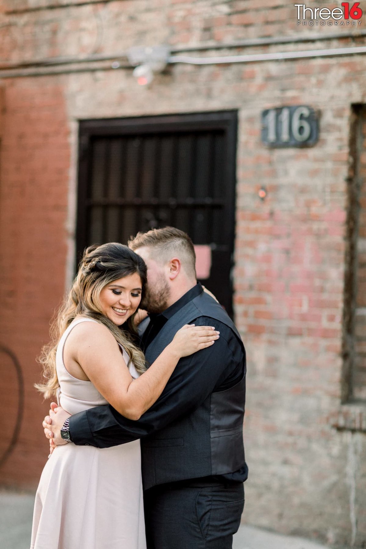 Groom to be whispers in his fiance's ear causing her to smile