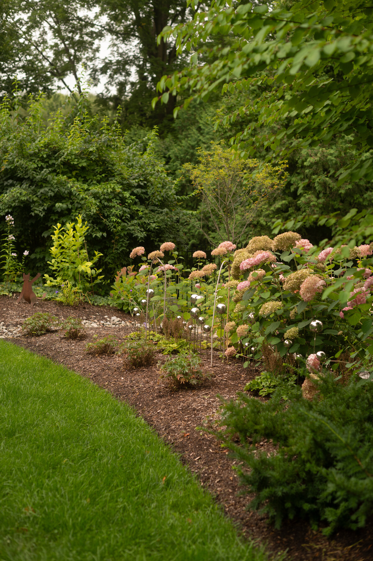 a landscaped garden and backyard with mulch, shrubs, plants by Helena's Gardening