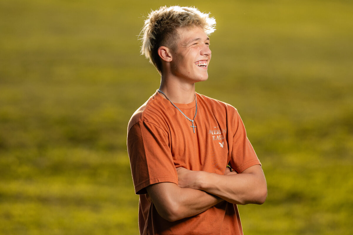 Pittsburgh senior photography of a senior smiling off camera right in a field at brush creek park