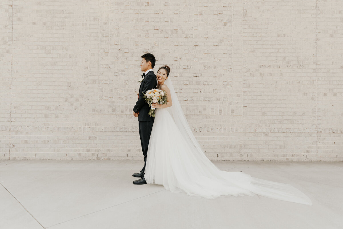Bride and groom in front of brick wall