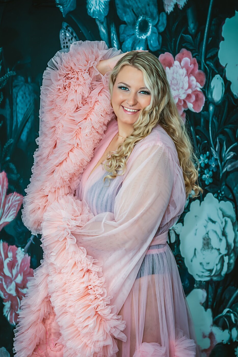A woman in a pink tule robe poses during her boudoir shoot.