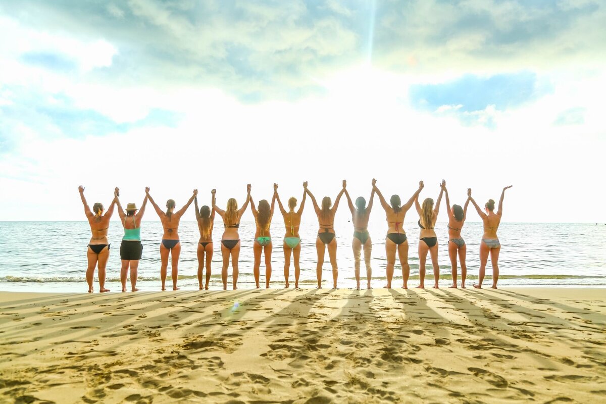 Group of women holding hands on a beautiful tropical beach