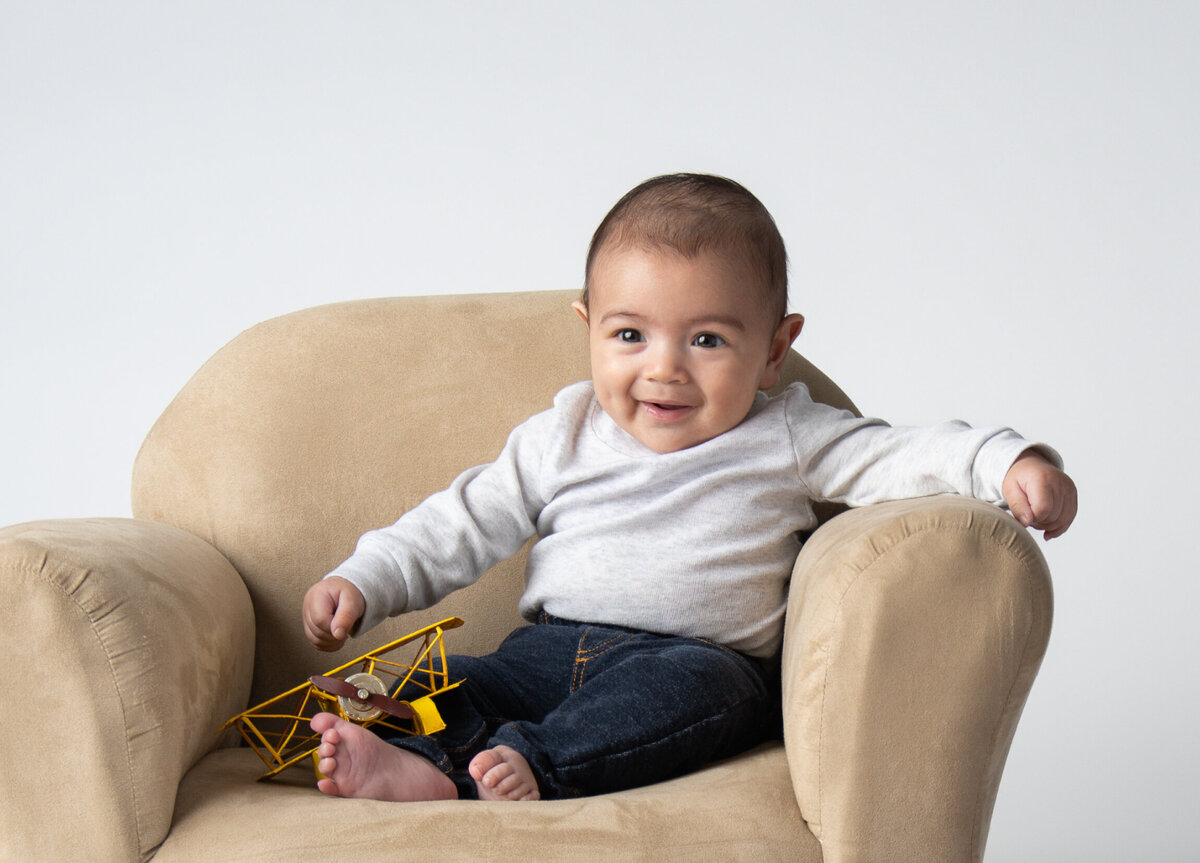 Cute 4 month old setting on a brown couch with